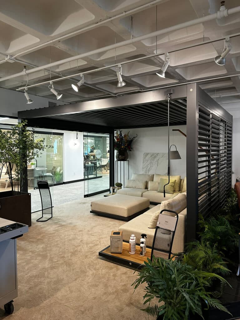 Aluminum pergola with louvers and modern outdoor furniture on display in a showroom