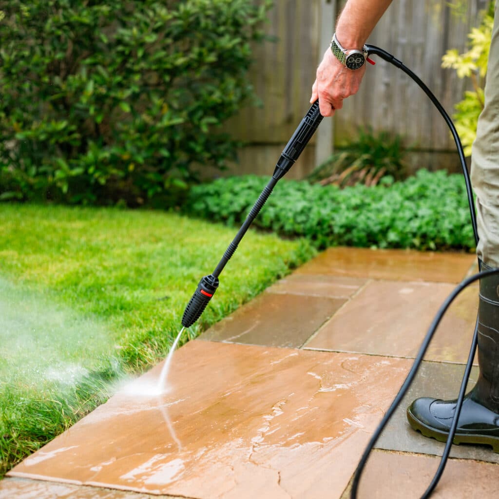 Man power washing natural stone pavers